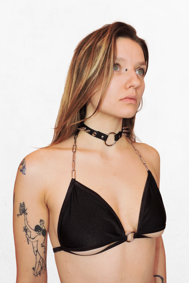 Close-up of a black strappy bikini with silver chain details. The top has an underboob cutout and a metal O-ring in the middle, adding a bold, alternative edge. Perfect for festivals, beach days, or standing out at the pool.