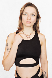 A fitted black top with a half-circle cutout beneath the bust, held together by an elastic band. The minimalist design shows off just the right amount of skin, perfect for creating a bold, edgy look.