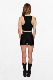 Close-up of a pair of black shorts with strategically placed cutouts on the hips. The stretchy fabric fits snugly and moves with the body, creating a bold, alternative silhouette.