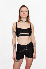 Model wearing a black top with a half-circle underboob cutout. The stretchy fabric fits snugly, creating a sleek silhouette while the cutout adds a provocative touch.